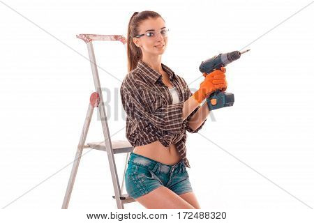 a young girl in a Plaid Shirt and glasses holding a drill near the stairs standing isolated on white
