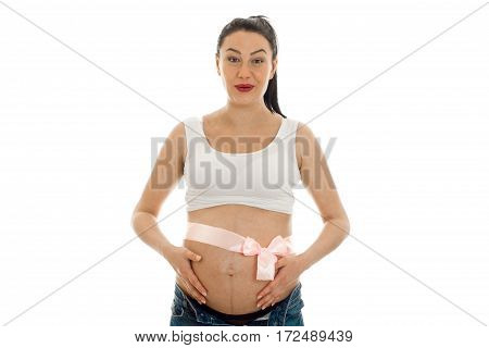 a young pregnant woman in white shirt stands up straight with a Ribbon on stomach isolated on white