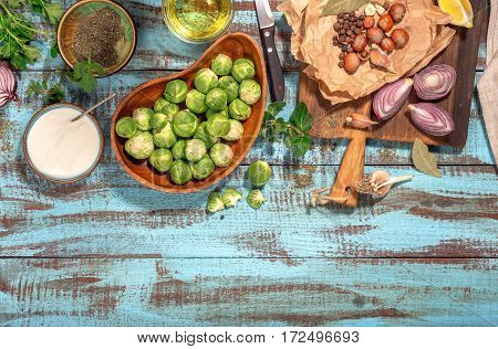 Brussels sprouts with ingredients for cooking tasty and healthy food on wooden table with border top view. Healthy food