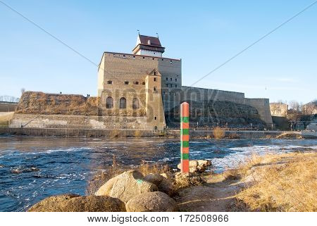 NARVA, ESTONIA - JANUARY 3, 2017: Hermann Castle Museum near The Narva (Narova) River which is the border between Estonia and Russia. Foreground is a boundary post in Russian town Ivangorod