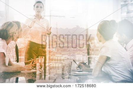 Businesswoman giving explication in front of a growing chart on a whiteboard during a meeting
