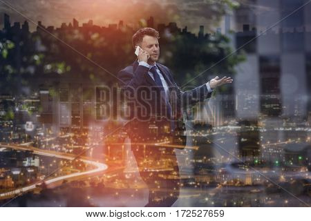Confused businessman communicating on mobile phone at street