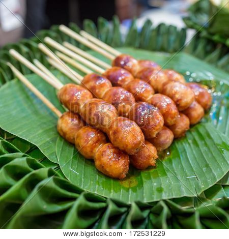 Traditional Thai style grilled Sausages on the banana leaf. Isaan pork meat sausage.
