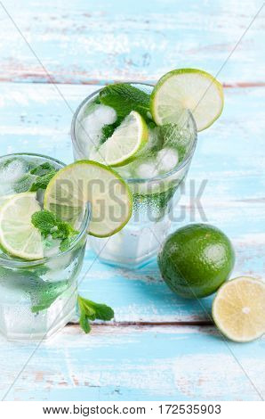 Mojito lime cocktail in bar on rustic wooden backgroung. Ingredients for making mojito. Summer refreshing drink