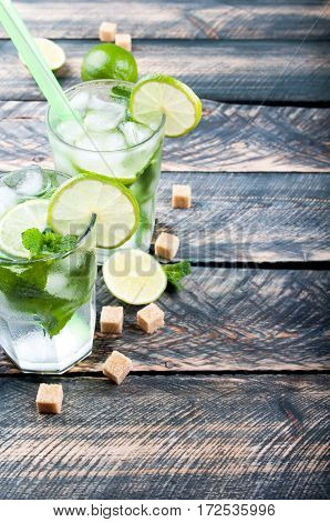 Summer cool drink mojito cocktail on rustic table. Ingredients for making mojito - lime and cane sugar. Copy space. Selective focus.