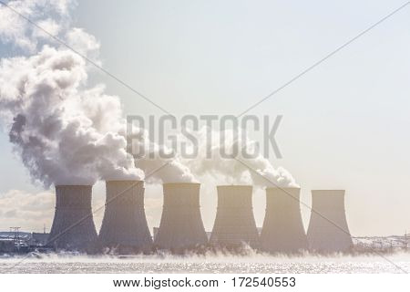 Cooling towers of a Nuclear Power Plant or NPP with thick smoke on blue sky background in sunny day. Copy space for text