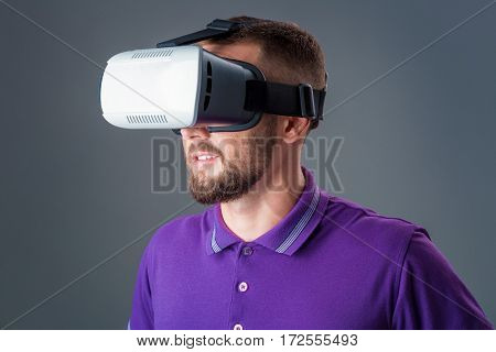 Man in studio wearing virtual reality headset playing game. Man dressed in a purple T-shirt