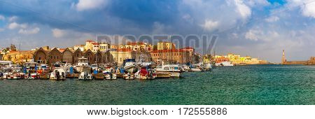 Panorama of Chania Arsenals, the Venetian shipyards, and fishing boats in old harbour of Chania in sunny and cloudy summer morning, Crete, Greece