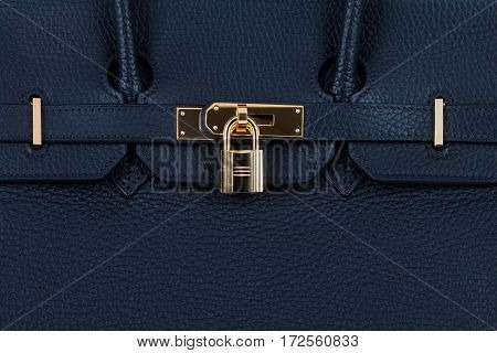 Closeup view of female blue leather handbag with golden clasp. Fashion background.