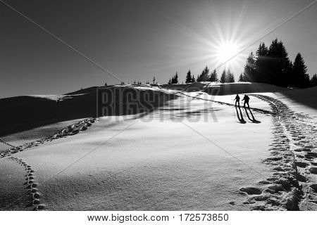 A couple hiking in a winterwonderland. After a gorgeous ascent they almost arrived at the summit cross of the mountain.