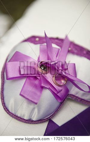 Wedding day.Beautiful wedding rings decorated with bows laying on pillow.