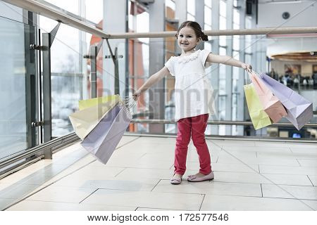 Young girl laden with paper shopping bags