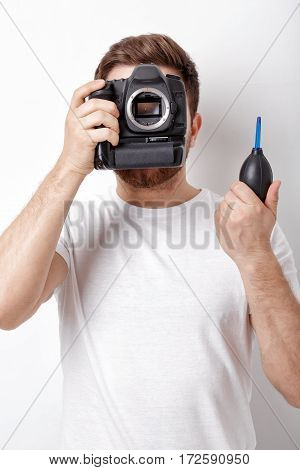 young photographer cleaning camera with vacuum pump. hand blower dust cleaner for camera and lenses.