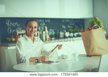 Young woman planning expenses and paying bills on her kitchen