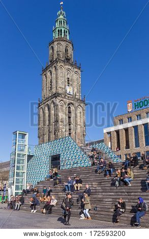 GRONINGEN, NETHERLANDS - FEBRUARY 15, 2017: People enjoying the spring sun in front of the Martini tower in Groningen, The Netherlands