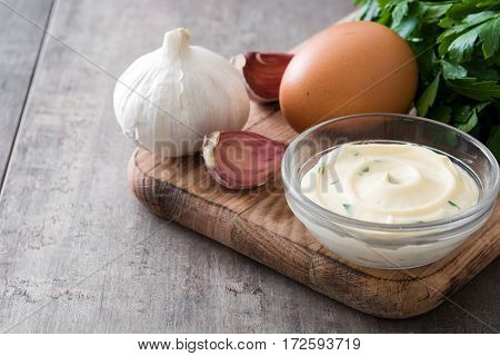 Aioli sauce and ingredients on wooden background