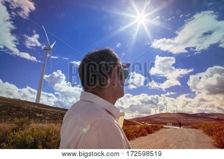 isolated man on a windmill area looking at new enviromental resources to obtain alternative energy.