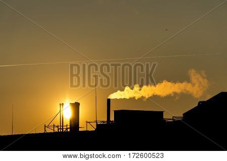 silhuette Industrial factory smoke from smokestacks over a colorful sunset sky industry