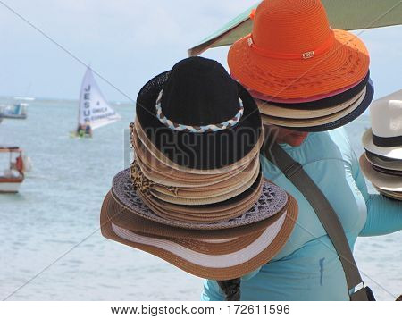 Seller of hats walking along the beach in Maceió, Brazil.