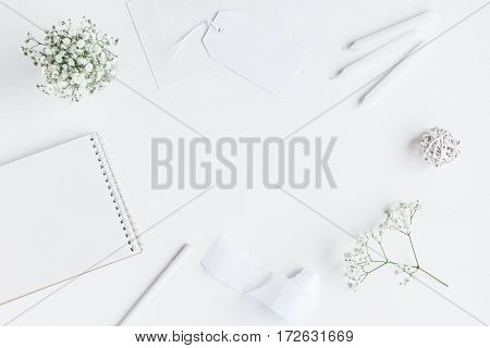 Workspace with notebook paper blank gypsophila flowers pencils. Wedding concept. Flat lay top view