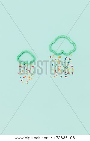 Greent clouds in shape of mold for the cookies with colorful bright confetti on blue background.