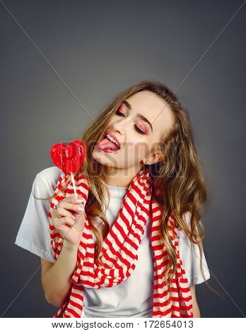 pretty girl in a red scarf pulled the tongue to candy. shot with copy space above head