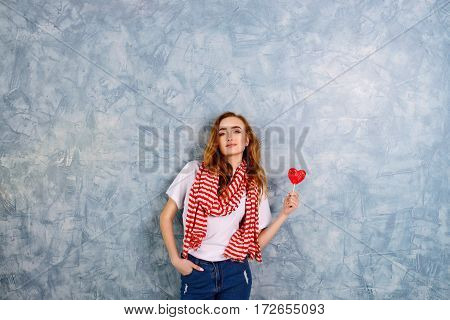 beautiful woman in a red and white stripped scarf holds candy . Wide shot with copy space