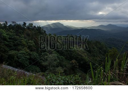 Sun rays over valley. Sun rays over hill. Tree in sun rays. Lonely tree. Tree with mountains in the background. Mountains in the background. Sunny clouds. Cloud eye. Dreamy landscape.
