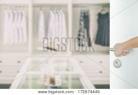 Man Hand Opening White Door To Closet Room With White Shirt And Hat On A Table