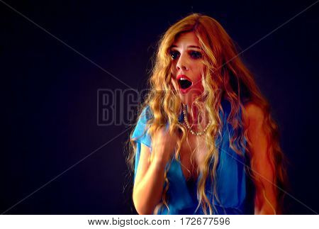Frightened woman screaming with fear indoor at halloween night. Horror. Girl with tousled hair bawl presses to her hands on black background.