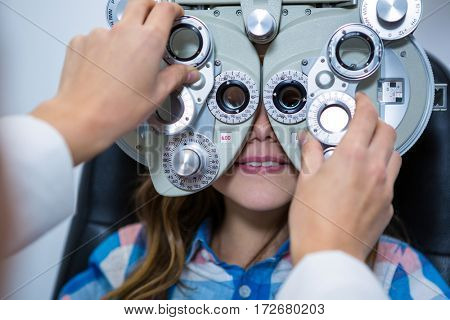 Female optometrist examining young patient on phoropter in ophthalmology clinic