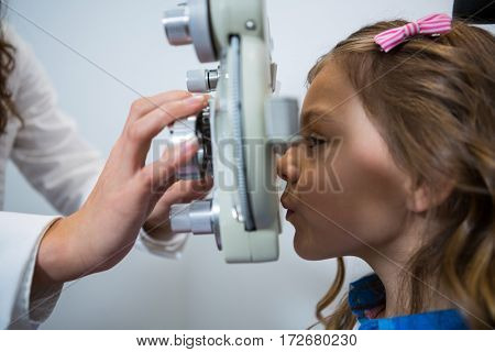Female optometrist examining young patient on phoropter in ophthalmology clinic
