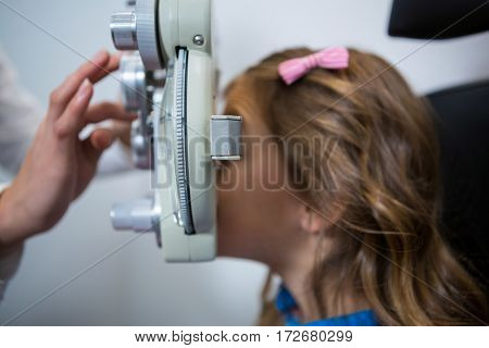 Female optometrist examining young patient on phoropter in ophthalmology clinic