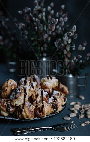 Still life with profiteroles and bouquets of pussy willow on dark background