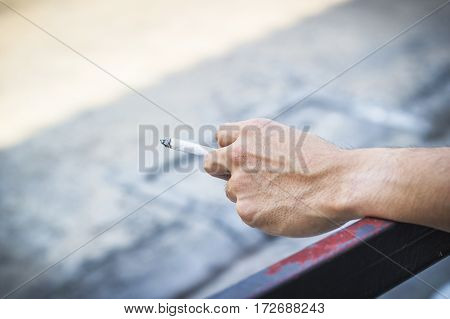 Man hand holding a cigarette smoking a cigarette with copy space.