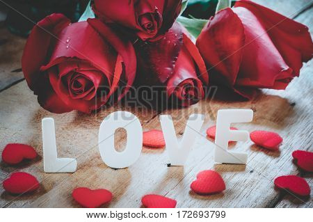 Caption word love heart and red rose on wooden board close up.Valentines Day background concept Wedding day.Vintage tone