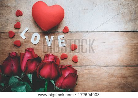 Caption word love red roses and heart on wooden background with copy space.Valentines Day background concept Wedding day.Top view vintage tone