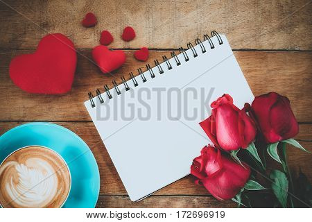 Red roses leather notebook penheart and cup of coffee on wooden background with copy space.Valentines Day background concept Wedding day.Top view vintage tone