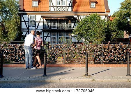 Gdansk Poland - July 19 2014: Couple on the bridge of love. Historical Miller's House on the background.