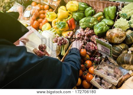Woman buying at outdoor French market the organic bio fresh Jerusalem artichoke (Helianthus tuberosus) also called sunroot sunchoke earth apple or topinambour is a species of sunflower native to eastern North America and found from eastern Canada and Main