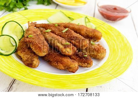 Deep frying small fish capelin on a plate on white wooden background. Close up