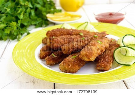 Deep frying small fish capelin on a plate on white wooden background. Close up