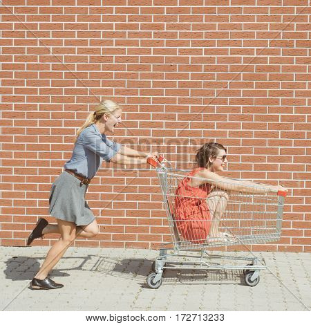 Friends having fun with shopping cart at a mall