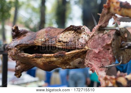 Barbecue picnic at country fair. Whole lamb roasted at spit. Grill, big piece of meat at rolling skewer. Street vendor food. Catering concept