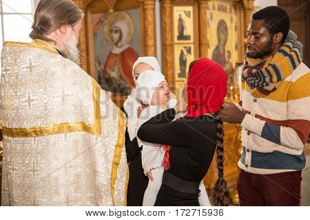 ALMATY KAZAKHSTAN - DECEMBER 17: Christening ceremony on December 17 2013 in Almaty Kazakhstan. Family celebrating baptism in Orthodox Church - Monastery of St. Matrona