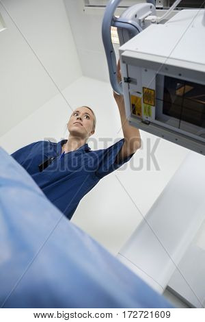 Low Angle View Of Radiologist Adjusting Xray Machine Over Patien