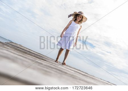 Girl with hat walking down the wooden walkway