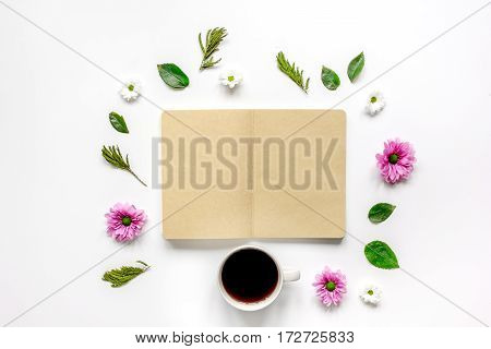 Flower petals, cup of coffee and brown craftpaper copybook on table background top view mock up