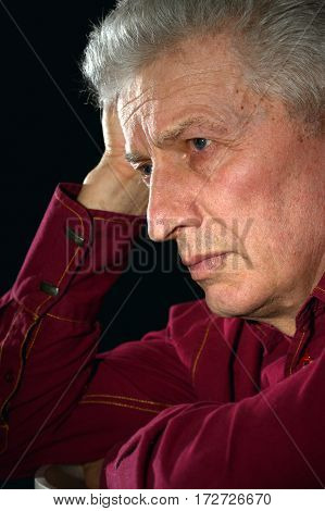 Portrait of a sad old man on a black background close-up