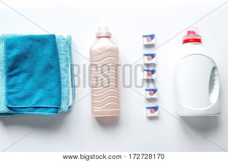 laundry set with bright towels and plastic bottels of detergent on white table background top view